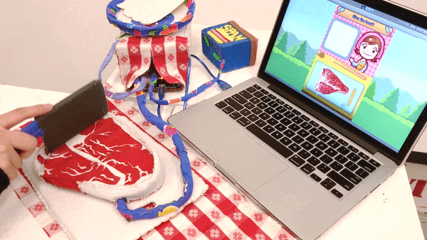 example gif of me using the cooking mama felt controller. I am chopping a felt steak, which triggers changes in the game running on the laptop
